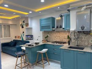a kitchen with blue cabinets and a blue couch at Appartement pour vacances in Boumerdes