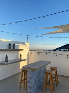 a table and two stools on a rooftop with a view at Acogedora y amplia casa, alberca climatizada previa reserva in Juriquilla