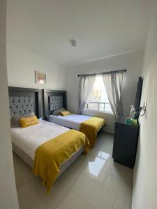 Duas camas num quarto com lençóis amarelos e uma janela. em Acogedora y amplia casa, alberca climatizada previa reserva em Juriquilla
