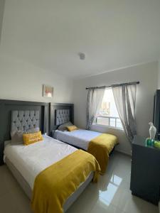 2 łóżka w sypialni z żółtą pościelą i oknem w obiekcie Acogedora y amplia casa, alberca climatizada previa reserva w mieście Juriquilla