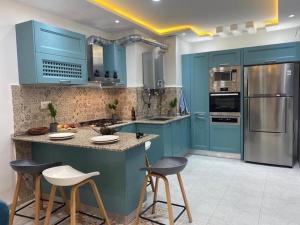 een keuken met blauwe kasten en barkrukken bij Appartement pour vacances in Boumerdès
