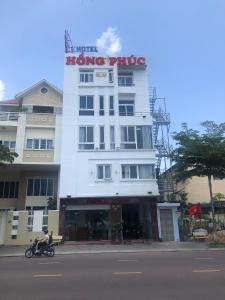 a man riding a motorcycle in front of a building at Hong Phuc Hotel in Quy Nhon