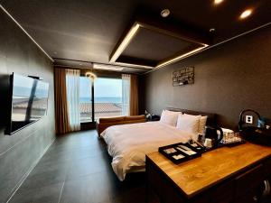 Schlafzimmer mit einem Bett und einem Schreibtisch mit einem TV in der Unterkunft Gyeongnam goseong Hotel With7 in Goseong