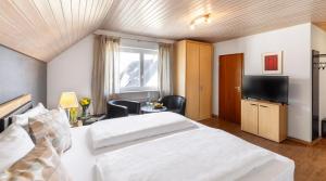 una camera d'albergo con due letti e una televisione di Hotel Garni Sonnengruss a Hagnau
