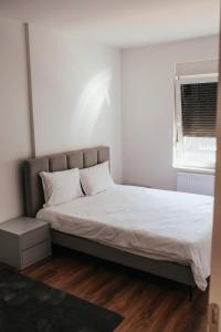 uma cama com lençóis brancos e uma janela num quarto em Apartment Prishtina 038 em Pristina