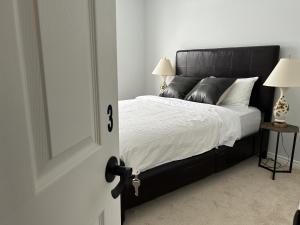 a bedroom with a black bed with white sheets and pillows at Kolopizo Lounge - Deluxe Queen in Ottawa