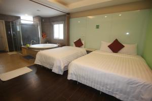 a bedroom with two beds and a bathroom with a tub at Kenting Waterfront Hotel in Kenting