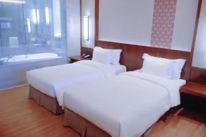 two beds in a hotel room with a bath tub at Neodalle Zhangjiajie Wulingyuan in Zhangjiajie