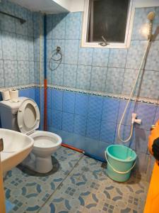een blauw betegelde badkamer met een toilet en een wastafel bij Cebu Pungko-pungko Hostel in Cebu City