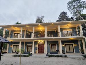 Cette grande maison dispose d'un balcon et d'une porte rouge. dans l'établissement Villa Forever Coorg, à Madikeri