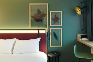 ヴィレンヌ・シュル・セーヌにあるCampanile Villennes-Sur-Seine - Poissy - Hôtel rénové en 2024のベッドルーム1室(ベッド1台付)が備わります。壁に4枚の写真が飾られています。