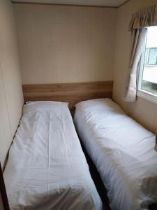 Norfolk broads caravan sleeps 8 في Belton: سريرين يجلسون بجانب بعض في غرفة النوم