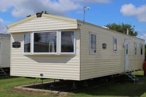 ein weißer Wohnwagen auf einem Hof parkt in der Unterkunft Norfolk broads caravan sleeps 8 in Belton