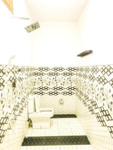 a bathroom with a toilet and a tiled wall at Lucky Bay in Arugam Bay