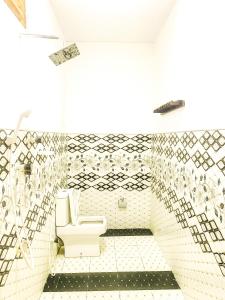 baño con aseo y pared de azulejos en Lucky Bay, en Arugam Bay