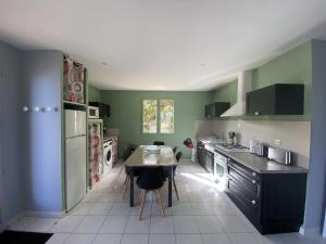 uma cozinha com paredes verdes e uma mesa em Gite Combe Ferrade en pleine nature em Campagnac-lès-Quercy