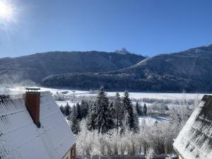 a snow covered roof of a building with mountains in the background at Das kleine Feriendorf in Carinthia