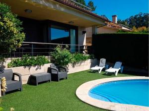 a yard with chairs and a swimming pool and a house at Casa con piscina Sanxenxo in Pontevedra
