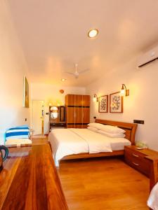 a bedroom with a large white bed and wooden floors at ODI KAMADHOO in Kamadhoo