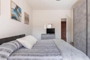 a large bed in a white room with a television at Dimora del Sole - Civico 13 in LʼAquila