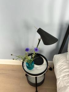 uma mesa com uma lâmpada e flores sobre ela em Elegant 1st Floor 1BR Belsize Park Apartment em Londres