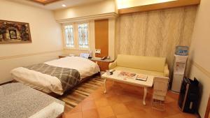 1 dormitorio con cama, mesa y sofá en ホテルシエル富士店 -大人専用-, en Fuji
