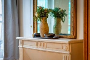 a dresser with a mirror and two vases with flowers at Charmant F2 rue du Gros Horloge à Rouen! in Rouen