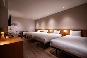 a hotel room with three beds and a television at hotel Bell・Kyoto in Kyoto