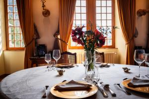 une table avec un vase de fleurs et des verres à vin dans l'établissement Château de Thorens, à Thorens-Glières