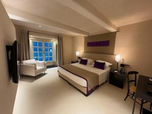 Großes Hotelzimmer mit einem Bett und einem Stuhl in der Unterkunft Hotel Palazzo Durazzo Suites in Genua