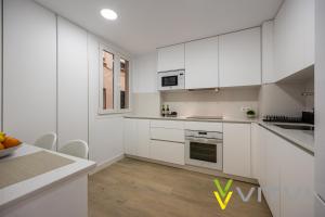 uma cozinha branca com armários brancos e uma mesa em Vitvi Fuengirola - Premium Reyes em Fuengirola
