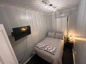 Chapter Homes Newcastle في Saint Peters: غرفة نوم صغيرة بها سرير وتلفزيون بشاشة مسطحة