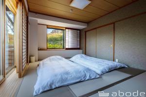 1 dormitorio con 1 cama grande y ventana en abode villa GORA 八代別邸, en Onsensō