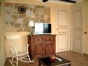 een woonkamer met een tv op een houten kast en een stoel bij Casa Roberto - Campagna Toscana vicino al mare in Castellina Marittima