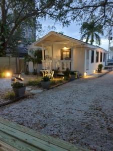 a small white house with a porch and a patio at Cracker Cow Cottages - Cottage A in Fort Myers