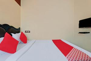 Schlafzimmer mit einem Bett mit roten Kissen und einem TV in der Unterkunft OYO Blooms Inn in Bangalore