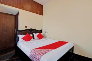 una camera da letto con un grande letto con cuscini rossi di OYO Blooms Inn a Bangalore