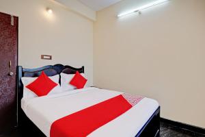 een slaapkamer met een rood en wit bed met rode kussens bij OYO Blooms Inn in Bangalore