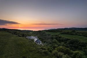 a house on a hill with the sunset in the background at Killoran House in Dervaig