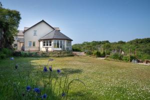 a white house with a yard with blue flowers at Killoran House in Dervaig