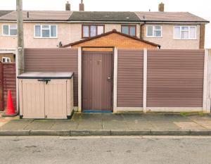 einen braunen Zaun mit einem Tor vor einem Haus in der Unterkunft Lux House in Peterborough