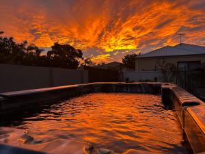 una piscina de agua con una puesta de sol en el fondo en Whitfords Delight Homestay, en Perth