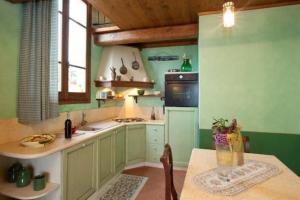 cocina con paredes verdes, mesa y horno en Appartement in Vinci mit Terrasse, gemeinsamem Pool und Grill und Panoramablick, en Vinci