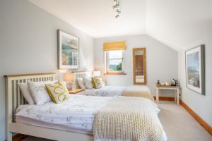 two beds in a room with white walls at Killoran House in Dervaig