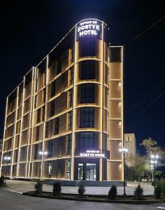 a building with a sign on top of it at night at Dostyk Business Hotel in Aktau