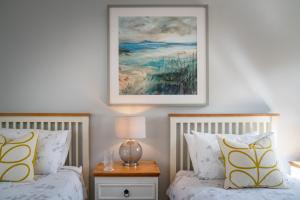 a bedroom with two beds and a picture on the wall at Killoran House in Dervaig