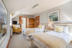 a bedroom with two beds and a chair at Killoran House in Dervaig