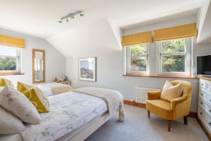 a bedroom with two beds and a chair and windows at Killoran House in Dervaig
