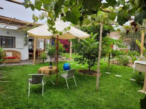 um jardim com uma mesa e cadeiras e um guarda-sol em Casa Huerta em Chincha Alta