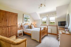 a bedroom with a bed and a tv and a chair at Killoran House in Dervaig